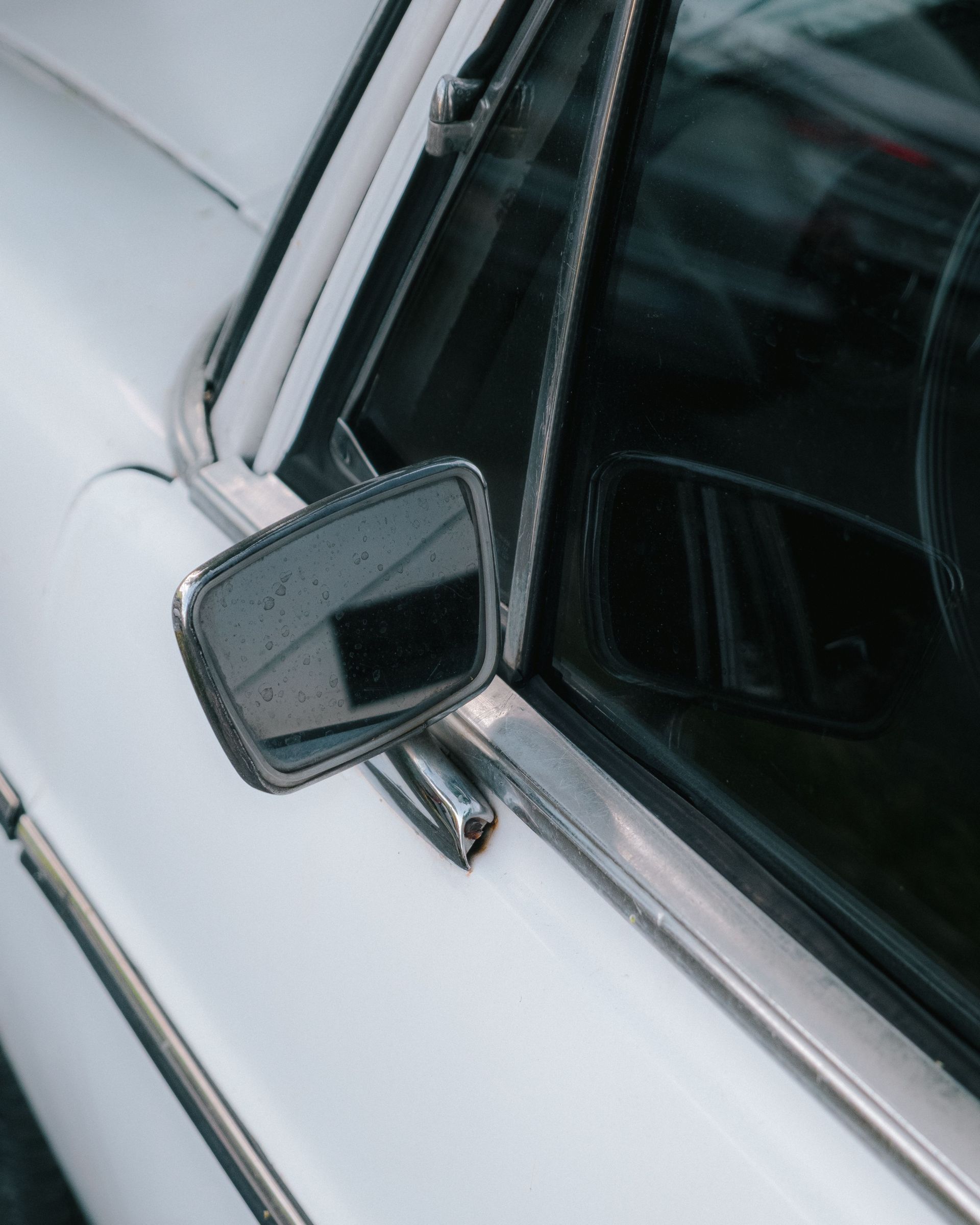 Detail of a vintage car's side mirror, showcasing timeless automotive design.