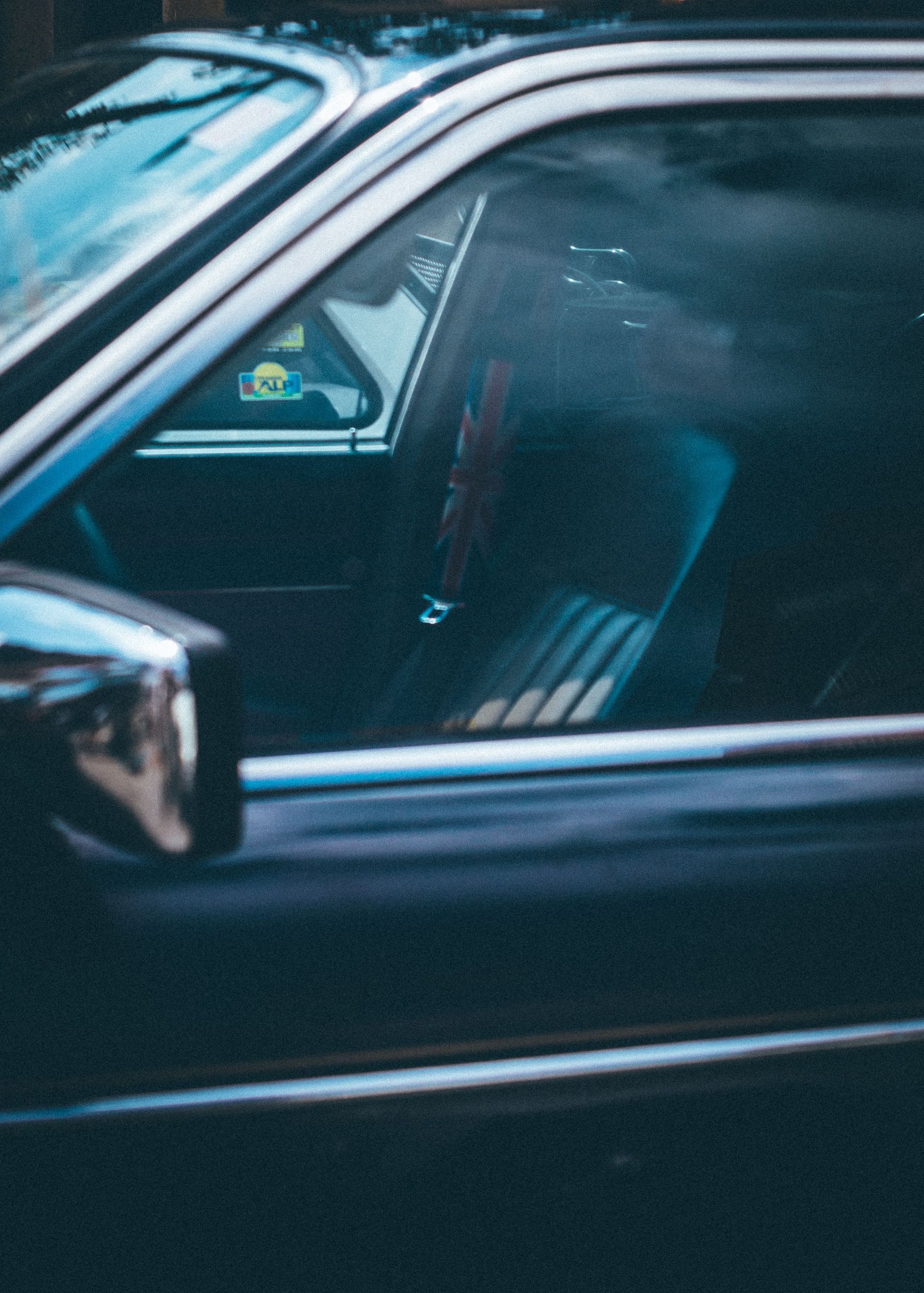 Close-up of a classic car interior featuring a Union Jack headrest and chrome accents.