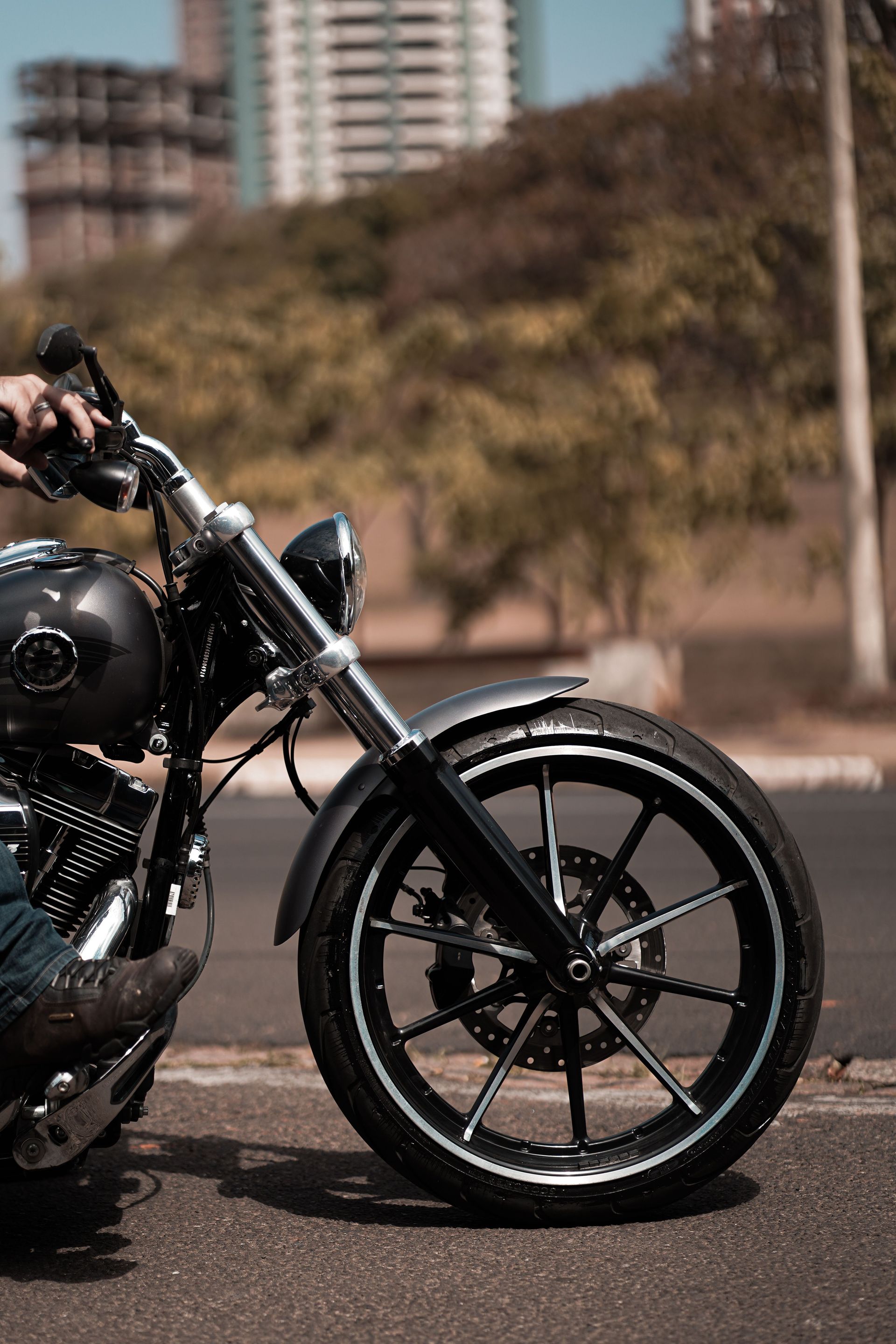 Detailed close-up of a motorcycle wheel with a rider on an urban road, capturing a dynamic city background.